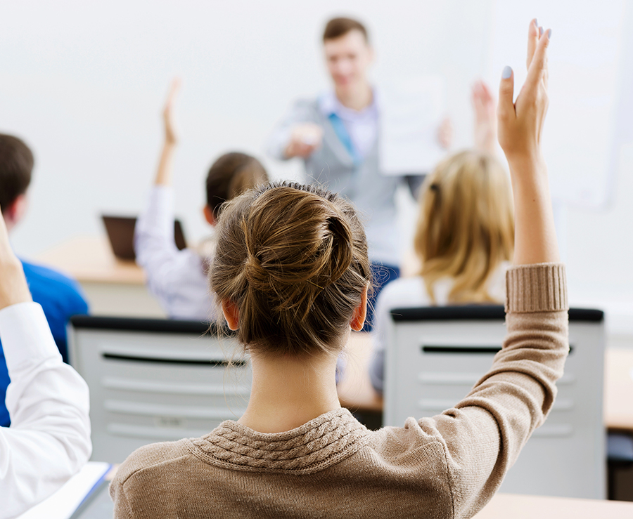 classroom-people-raising-hands-view-from-behind-students-instructor-blurred-at-front-ispeak